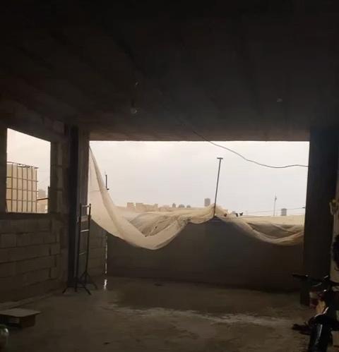 A room without glass in the window; torn plastic instead.